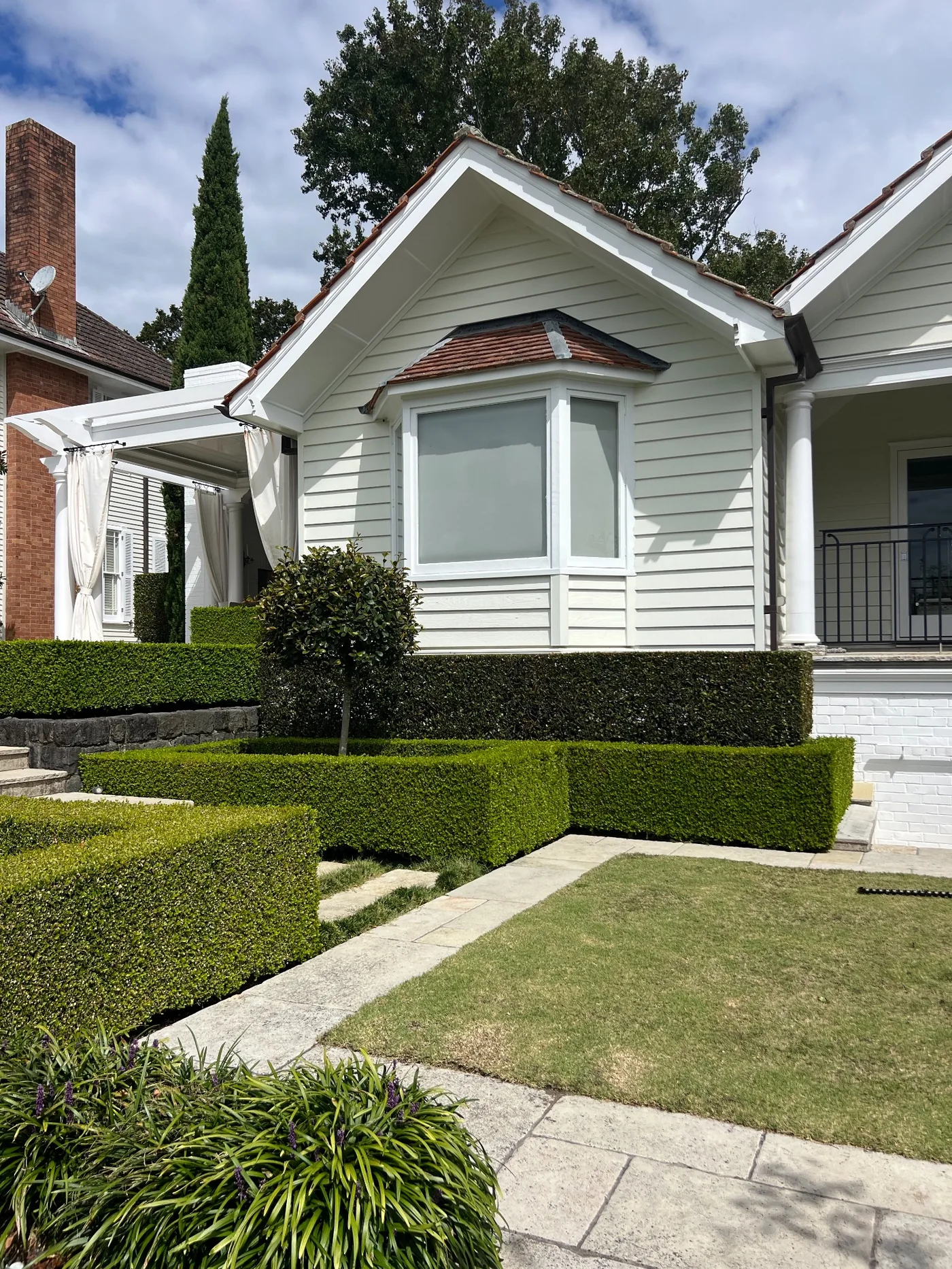 Trimmed hedges and lawn beside a premium Auckland home
